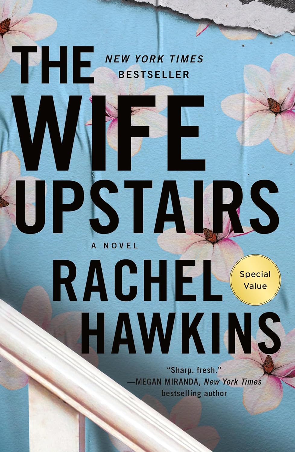 Cover of The Wife Upstairs by Rachel Hawkins featuring a light blue background with soft pink flowers, bold black title text, and a white staircase in the foreground. The cover highlights it as a New York Times bestseller and includes a review quote from Megan Miranda. Bookish Wonderland serves readers from every district of Bangladesh.