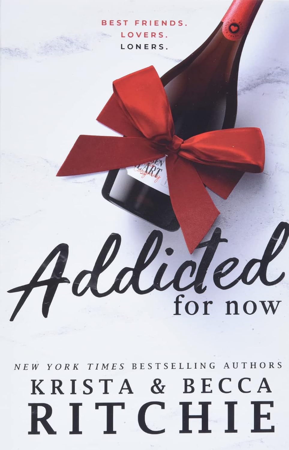 Cover of Addicted for Now by Krista & Becca Ritchie, Book 3 in the Addicted series, featuring a champagne bottle tied with a large red ribbon on a white background. The romance novel cover includes the tagline Best Friends. Lovers. Loners. above the title and the authors' names at the bottom. Bookish Wonderland supports knowledge and education in Bangladesh.
