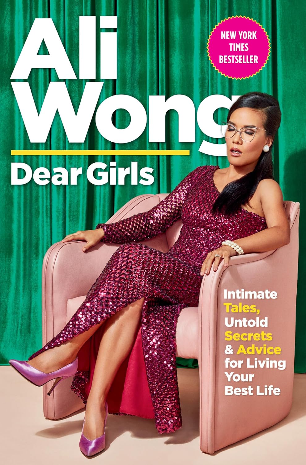 Book cover of 'Dear Girls' by Ali Wong with a woman in a sequin dress sitting on a pink chair which is available in BD.
