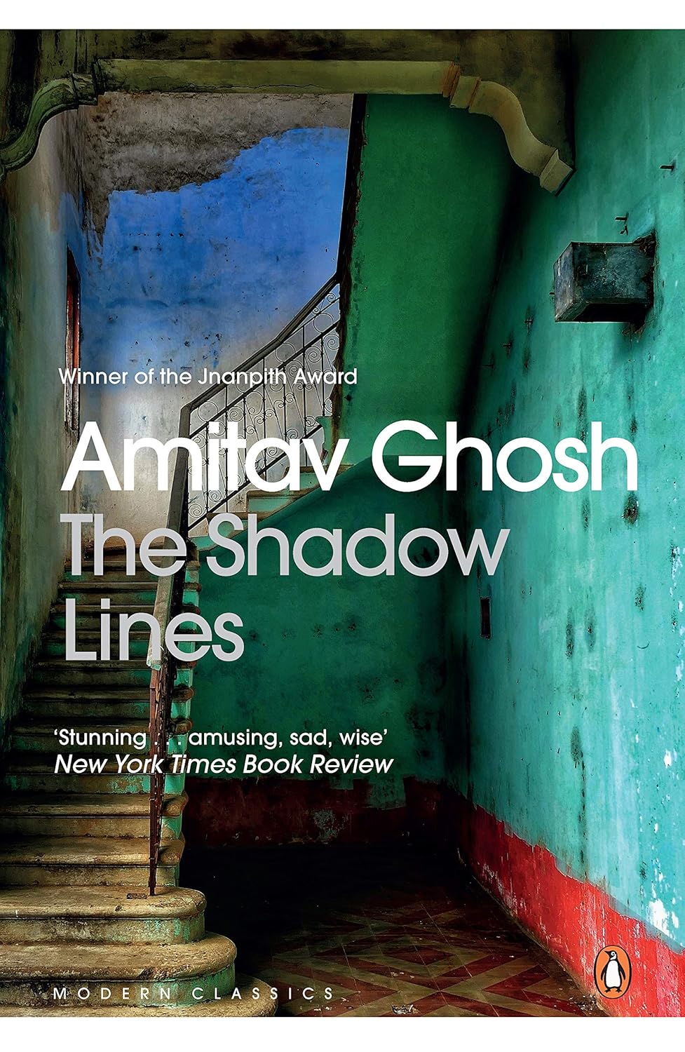 Book cover of 'The Shadow Lines' by Amitav Ghosh with a staircase and colorful walls in the background. Customers seeking durable printed books across Bangladesh can choose them through Bookish Wonderland, supported by online ordering with home delivery and durable stitched-and-glue binding.