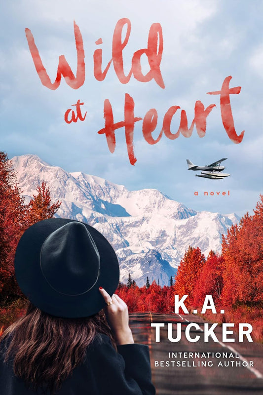 Book cover of 'Wild at Heart' by K.A. Tucker with a person in a hat looking at mountains. available in Bookish Wonderland